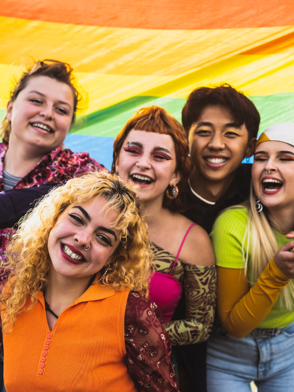 friends smiling with rainbow flag in the background